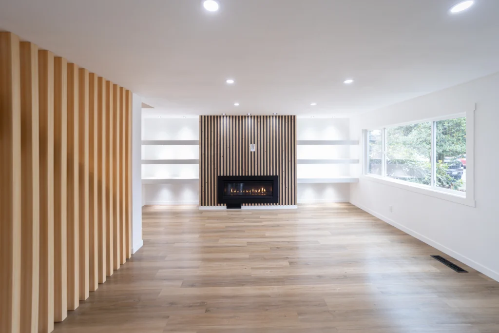 Open Living Room Area With Black Stone Fireplace & Horizontal Brown Wood Flooring